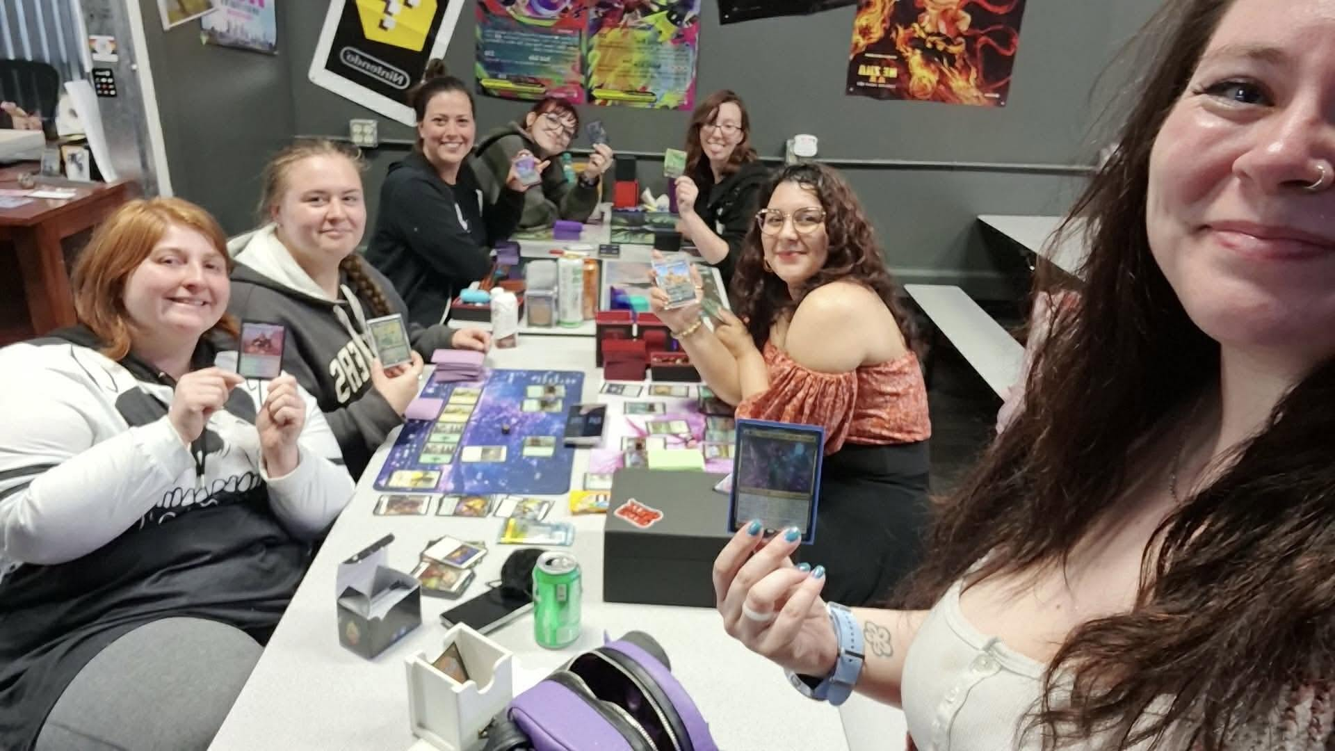 A group of players gathered around a table holding cards during a weekly game night